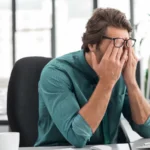 A man holding his face in frustration at the office