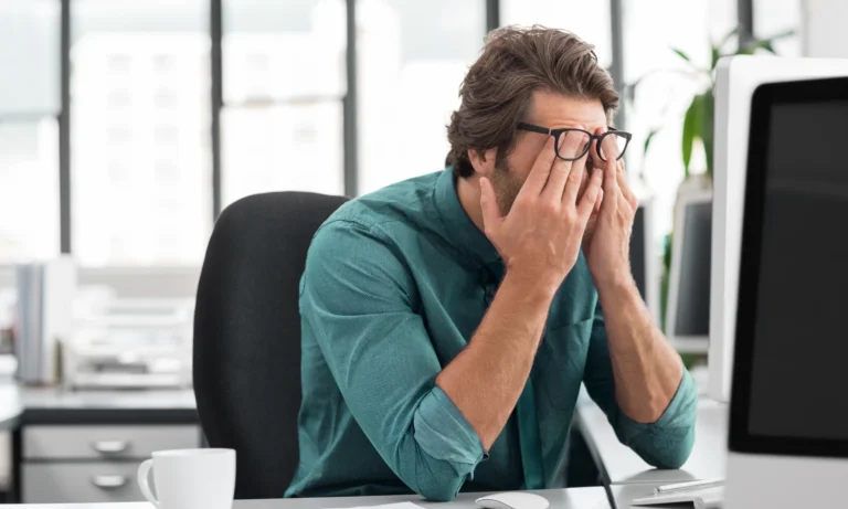 A man holding his face in frustration at the office